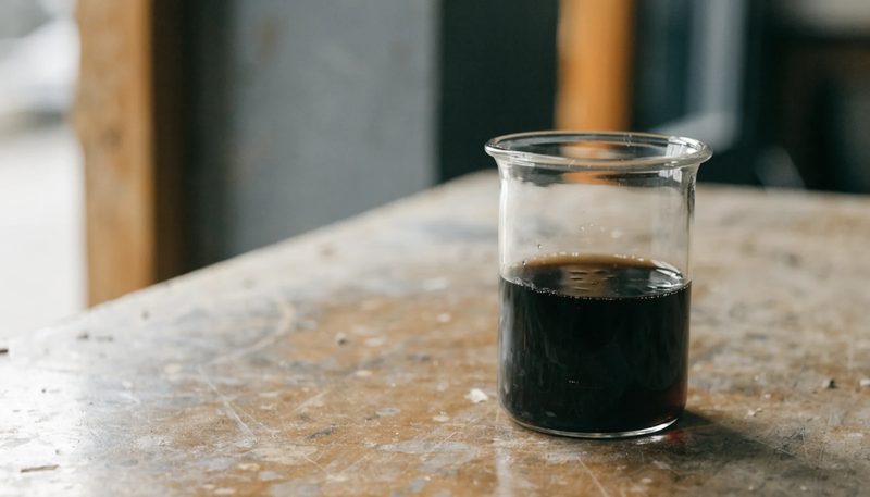 Dark wood vinegar condensate in a plain glass beaker.