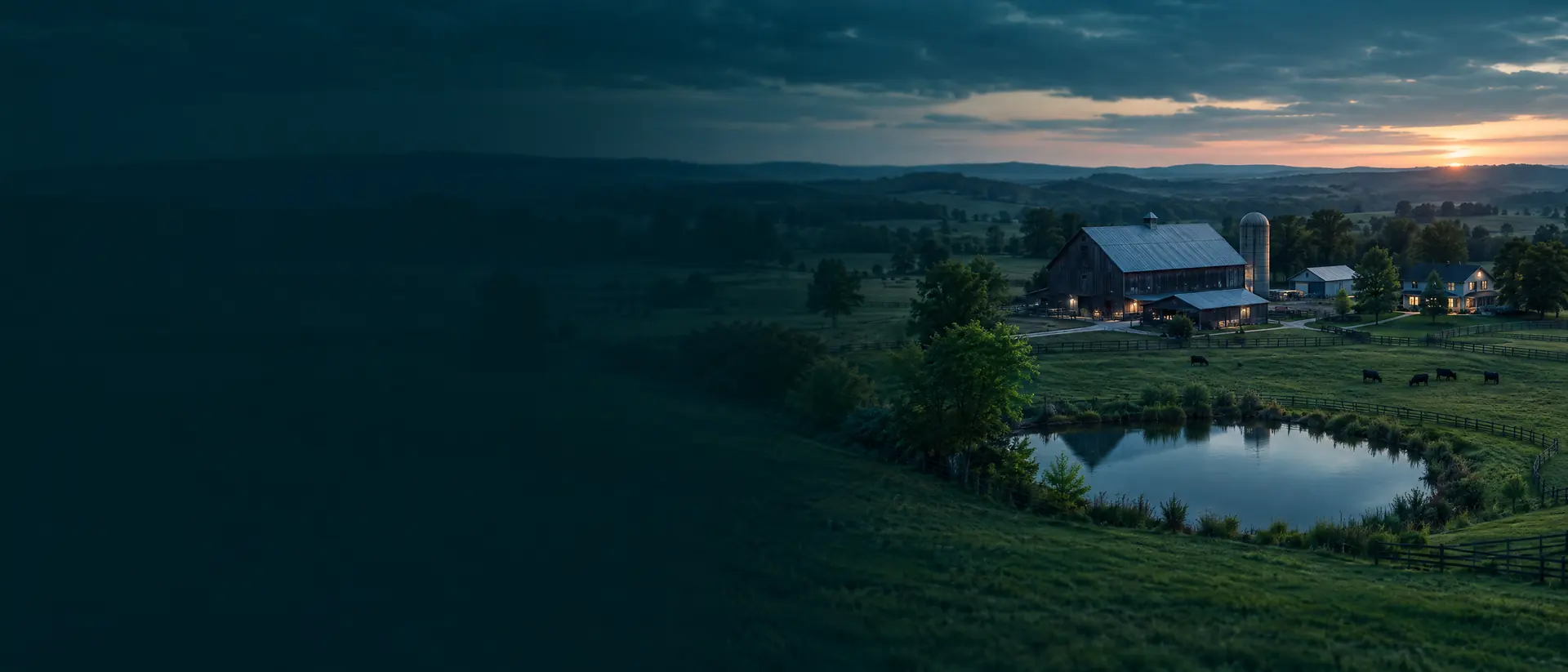 Aerial view of a farm with barn, pasture and pond at dusk