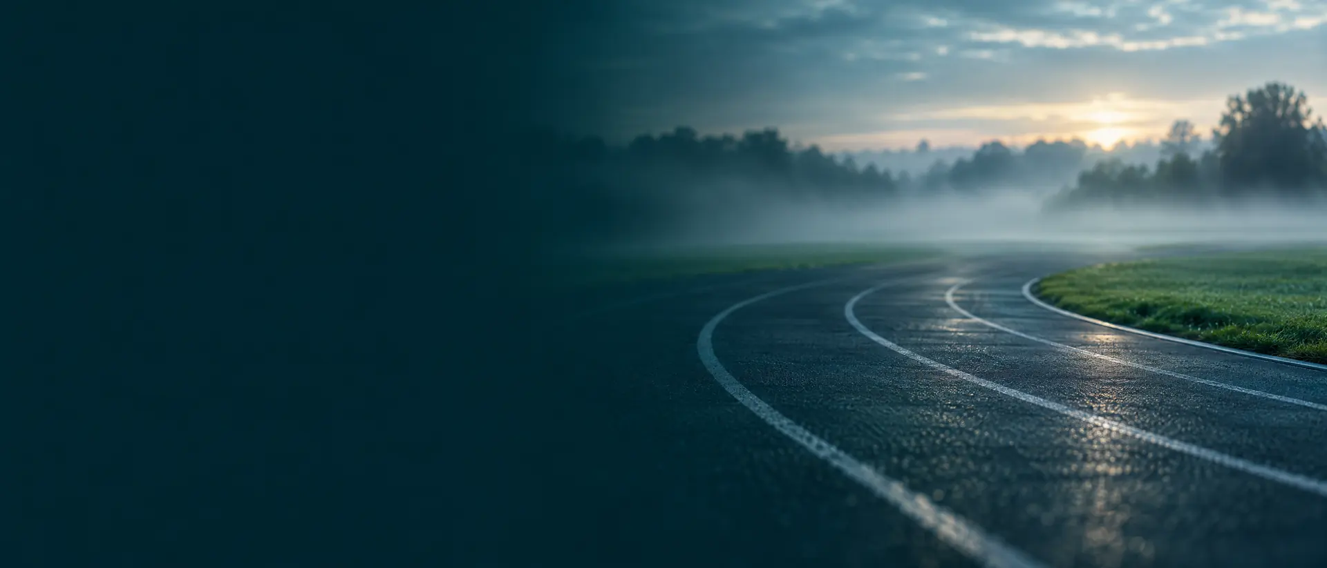 Empty running track at dawn with blurred lanes and mist over the field