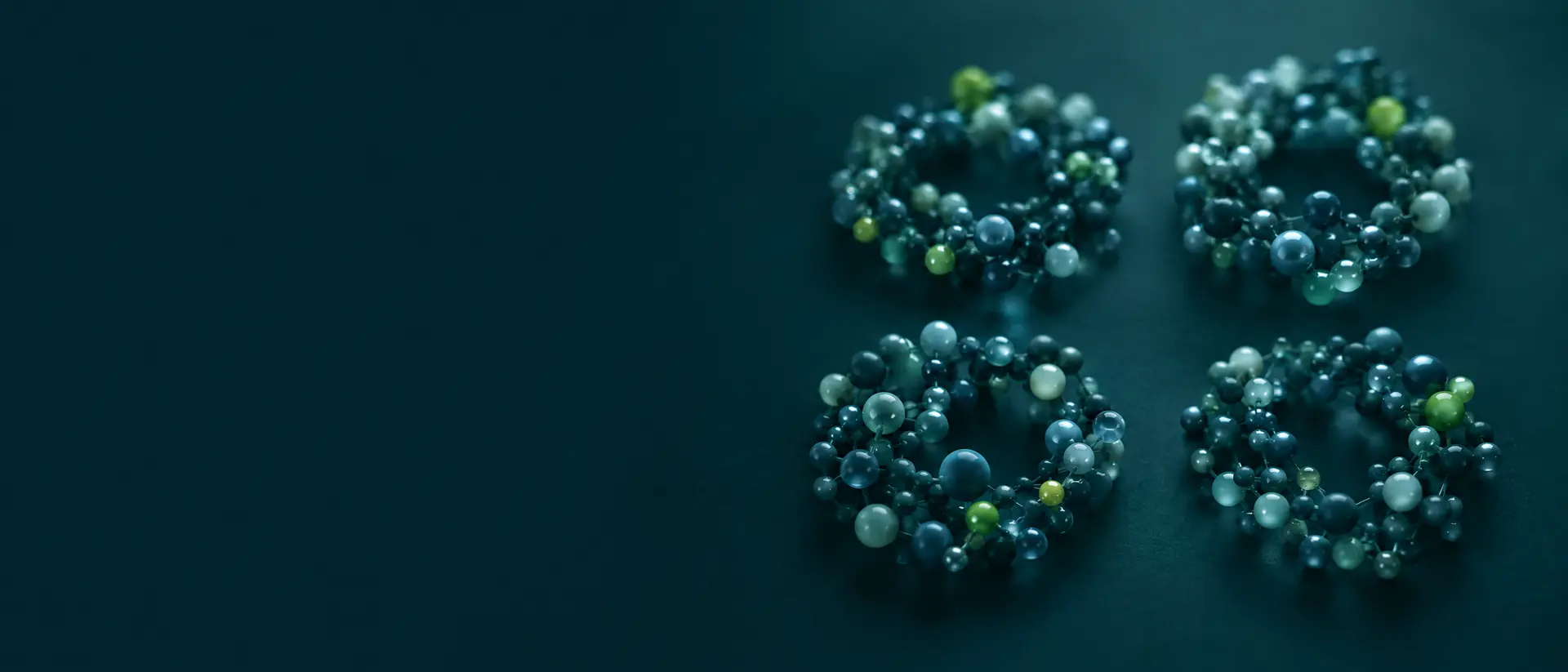Four clusters of bead-chain molecules arranged in soft circles on a dark teal plane