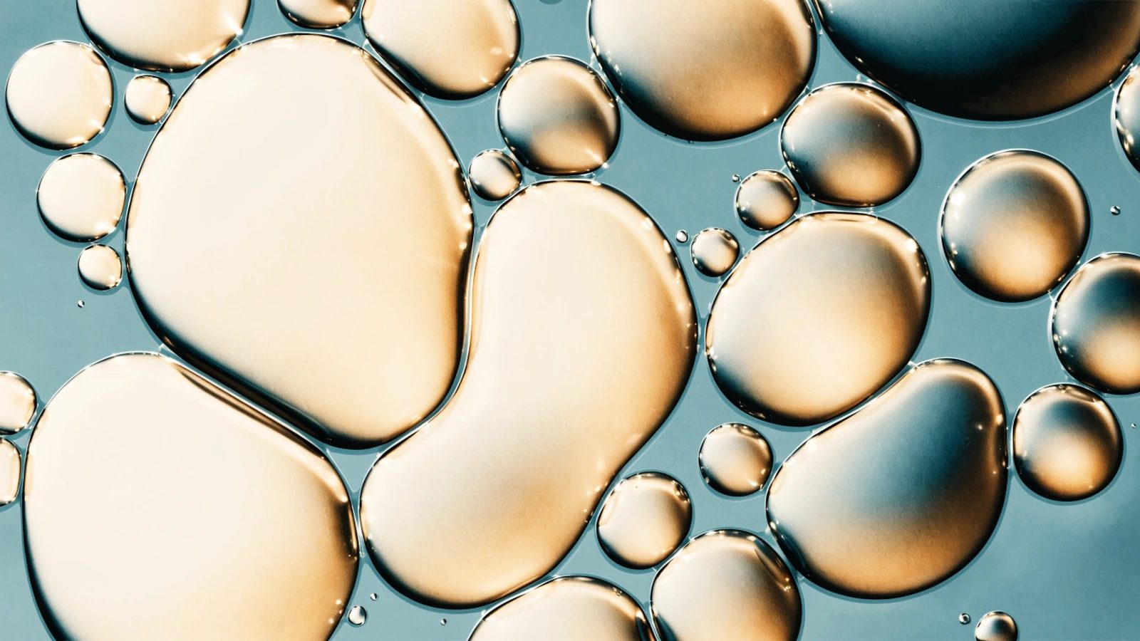 A decorative microscopic-texture image showing coalescing rounded oil droplets.